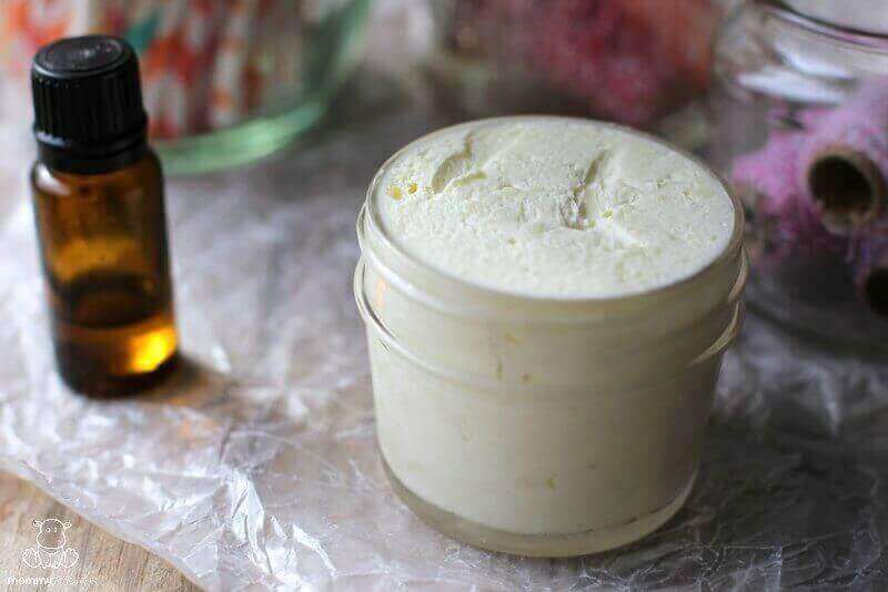 Tallow face cream displayed on a table beside a bottle of natural essential oil.