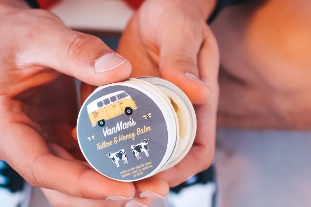 Man's hands holding an open jar of VanMan's Tallow and Honey Balm.